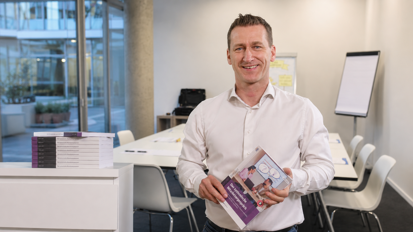 René Laxy hält sein Buch Das systemische Mitarbeitergespräch in den Händen